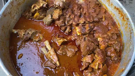 close up shot of delicious mutton curry dish in aa steel bowl during an indian function