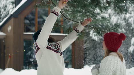 caucasian couple decorating garden by christmas in lights outdoors.