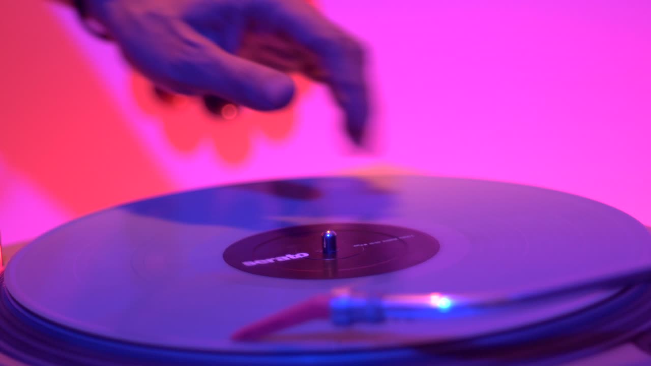 movimiento de giro y scratch realizado a mano en un tocadiscos de vinilo durante una actuación en vivo, filmado como un primer plano en la mano y en la plataforma de vinilo
