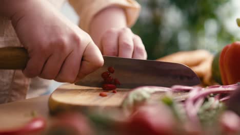 Frau-Schneidet-Chilischoten-Auf-Einem-Holzbrett.