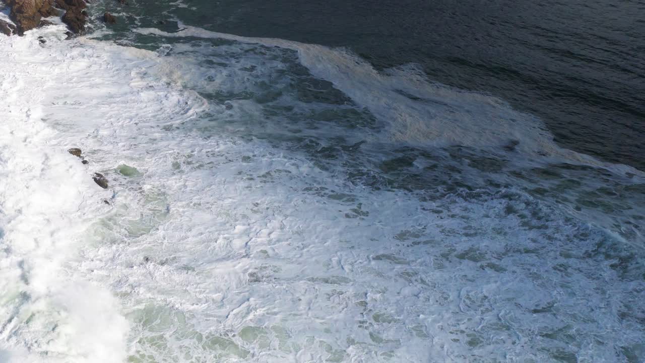Aerial view of powerful ocean waves crashing against rocky shoreline at Byron Bay, captured in natural daylight