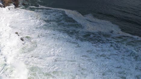 aerial view of powerful ocean waves crashing against rocky shoreline at byron bay, captured in natural daylight