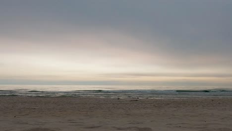 Peaceful beach scene at Smiltynė, Lithuania, with soft waves and pastel sky at sunset