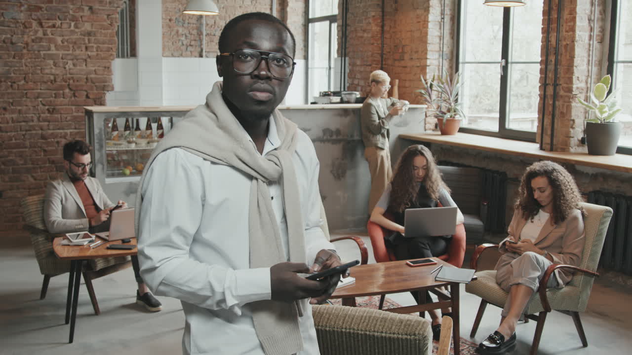 Black Man with Smartphone Posing for Camera in Coworking Office