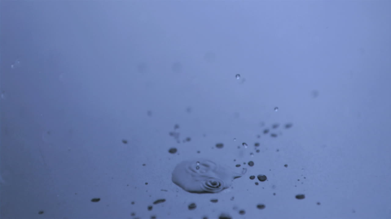 капля дождя в супер медленном движении падает в лужу.