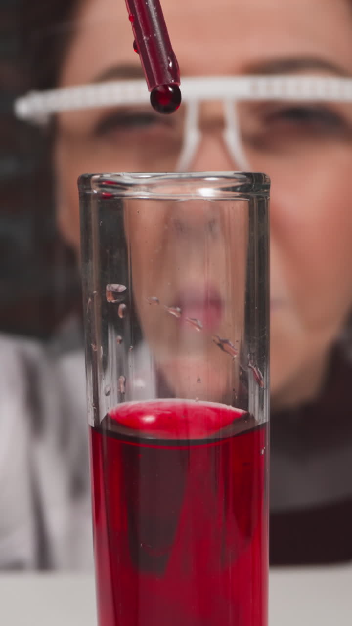 Lab assistant with goggles drips blood into test tube with reagent in laboratory slow motion. Probe lens shot of medical examining extreme closeup