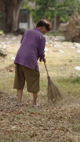 woman sweeping leaves outdoors