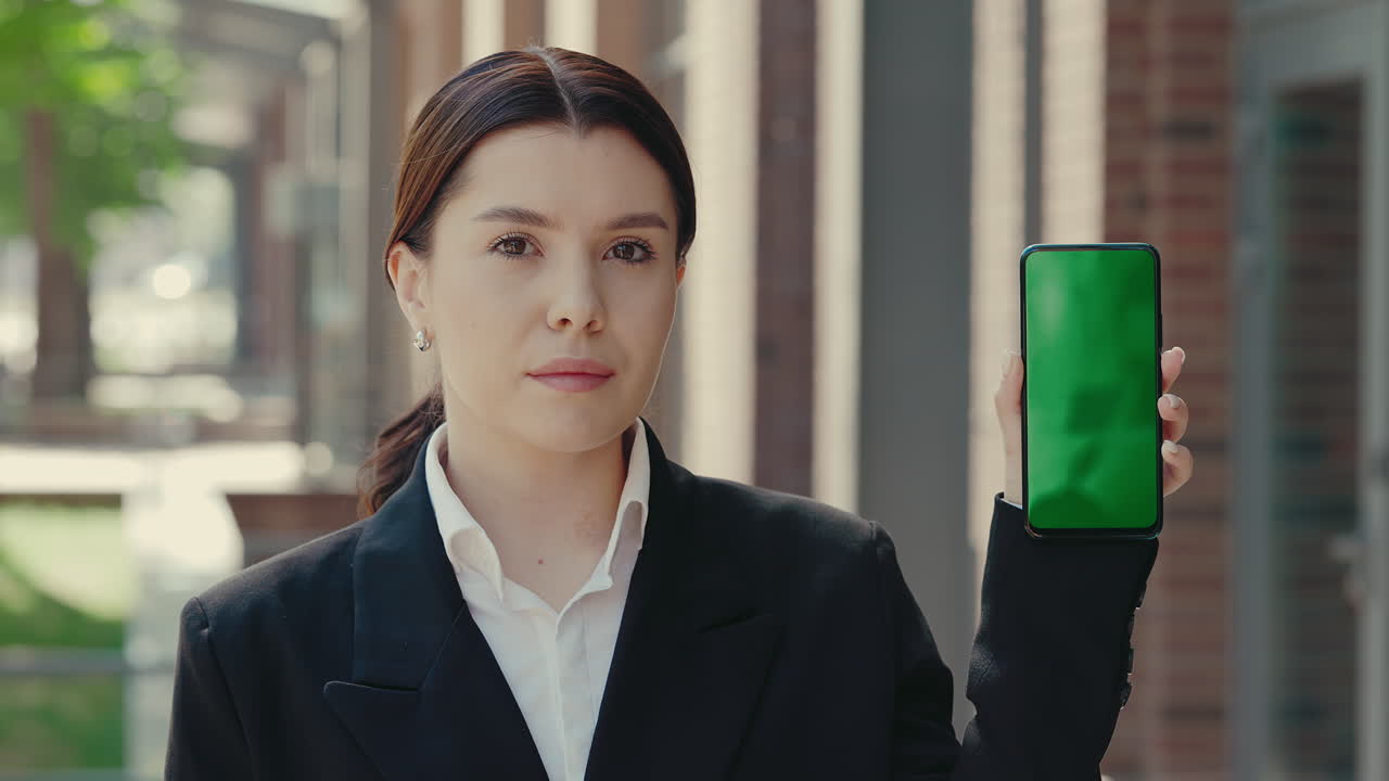 Businesswoman holding a smartphone with a green screen