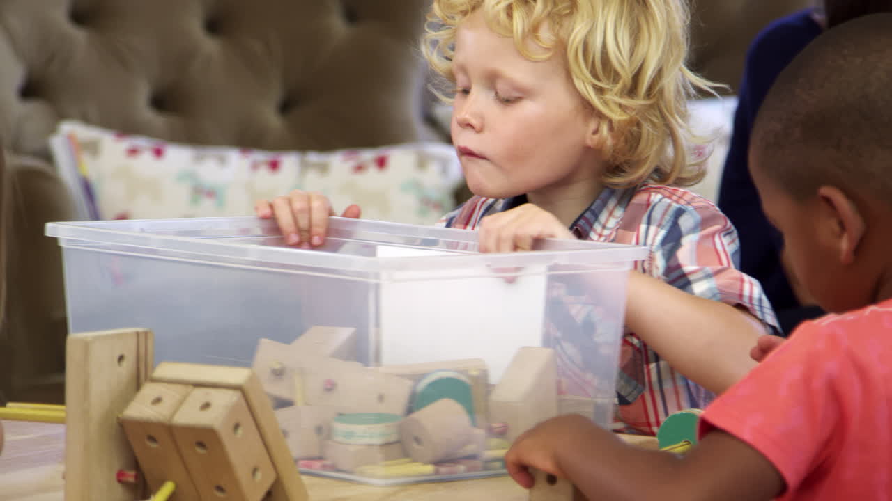 몬테소리 학교 학생 들 은 나무 건물 세트 를 가지고 책상 에서 일 한다