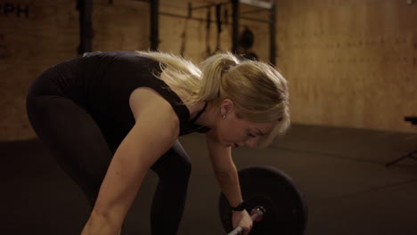 strong blonde woman in black does snatch weightlifting move, cinematic lighting