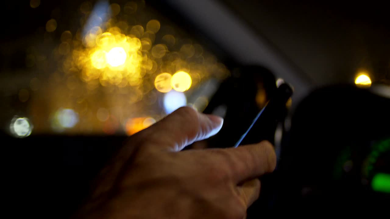 uso de teléfonos inteligentes mientras se conduce de noche en la ciudad