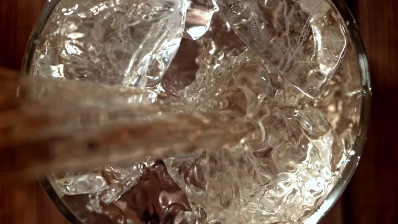 Acqua rinfrescante versata su cubetti di ghiaccio al rallentatore