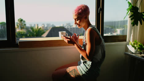 mujer sentada cerca de la ventana y usando el teléfono móvil 4k