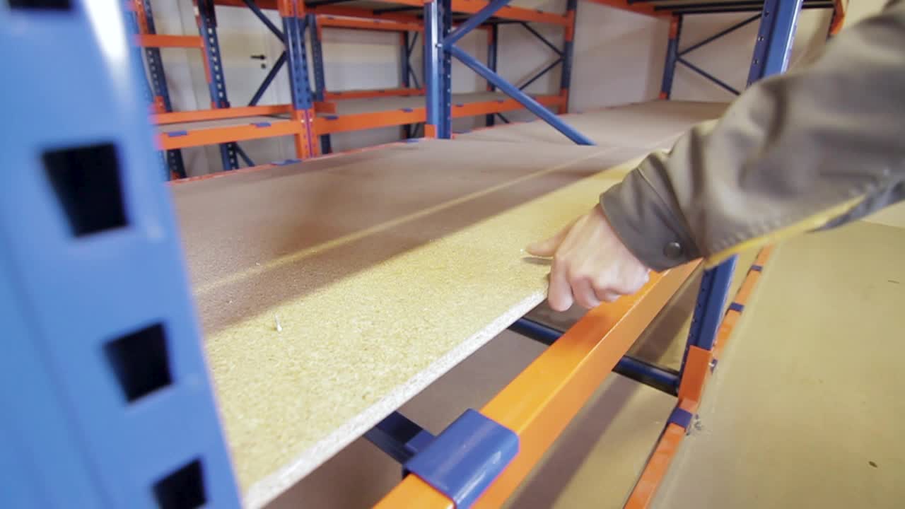 el trabajador pone una placa de madera en un estante.