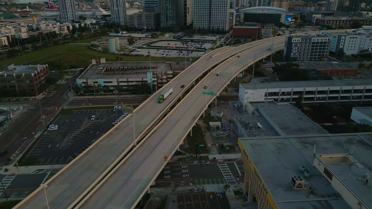 Drone in posizione elevata che si inclina lungo un'autostrada che attraversa il centro di Tampa con auto e semirimorchi che passano al tramonto