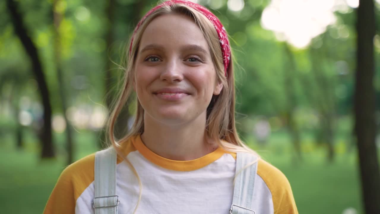 그녀의 미소를 가리키며 야외에서 윙크하는 꽤 명랑한 소녀의 초상화