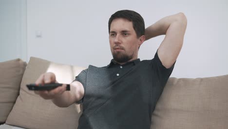 man relaxing on couch watching tv