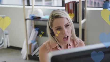 animación de corazones amarillos y azules sobre mujer de negocios caucásica usando auriculares de teléfono