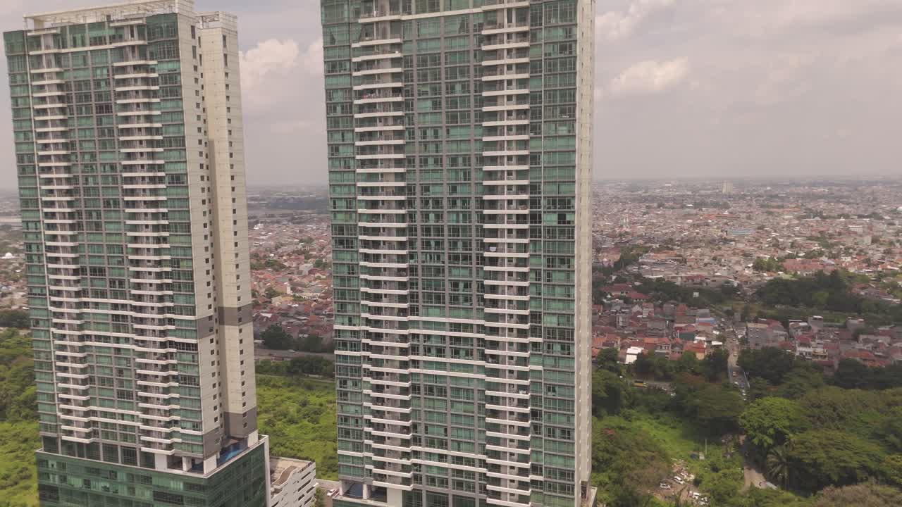 Breathtaking aerial zoom-out shot of twin high-rise residential towers in Tangerang, Indonesia, revealing modern architecture and vibrant cityscape views. Perfect real estate and urban projects.
