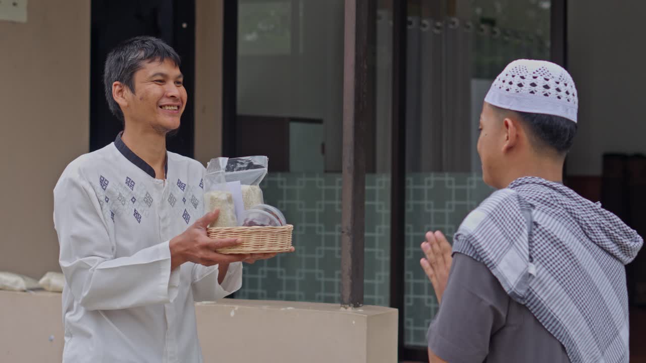 Uomo musulmano sorridente riceve un cesto di riso e cibo come donazione Zakat durante il Ramadan.