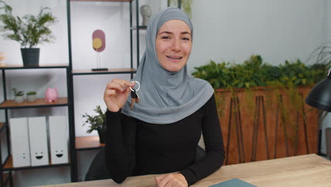 Muslim-woman-real-estate-agent-showing-keys-of-new-home-house-apartment,-buying-or-renting-property