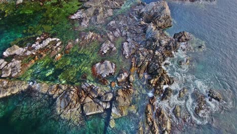 overhead hover view of dramatic detailed rock formations with ocean waves crashing