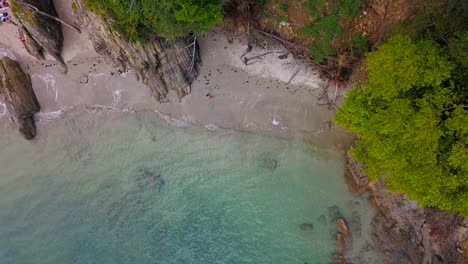 aerial birds eye view of lone person walking along secluded beach cove coastline