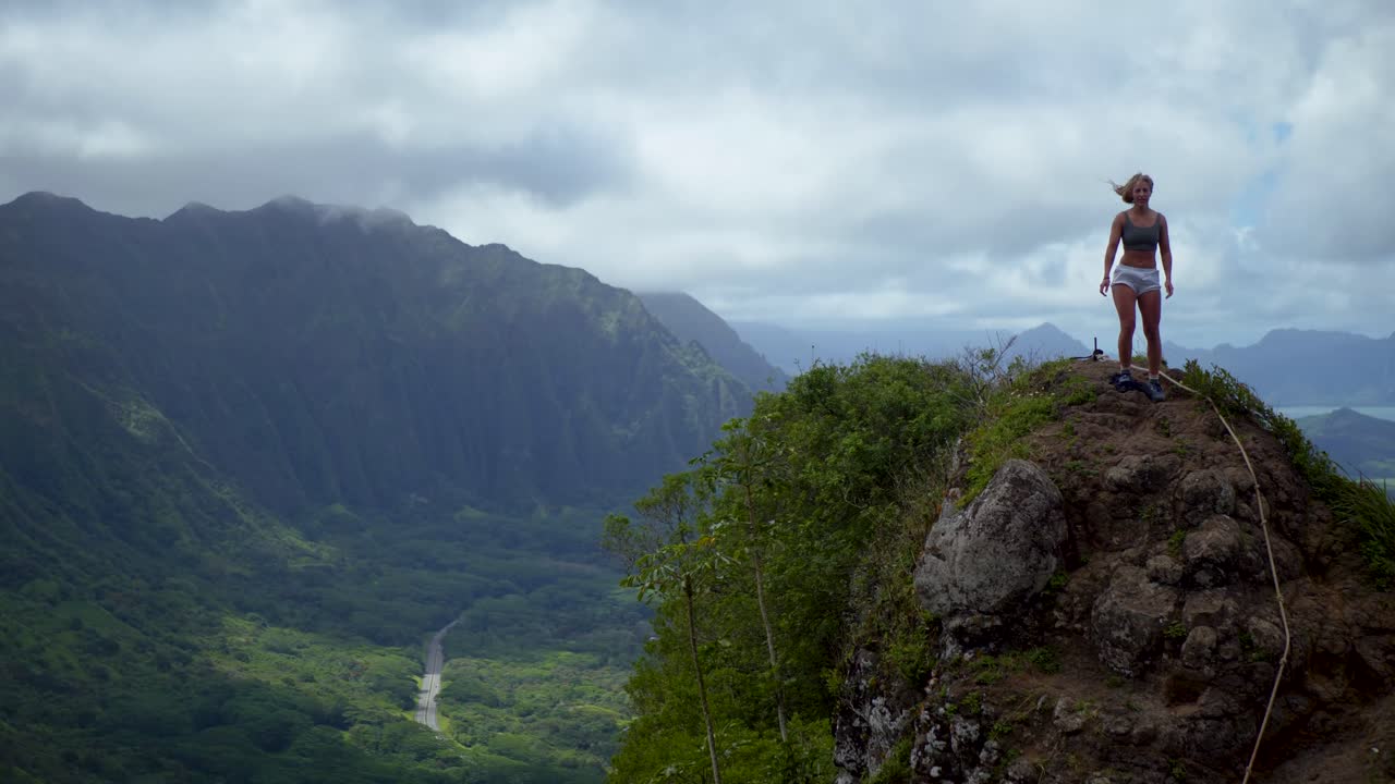 mujer en una caminata en hawai de pie en la cima de la montaña