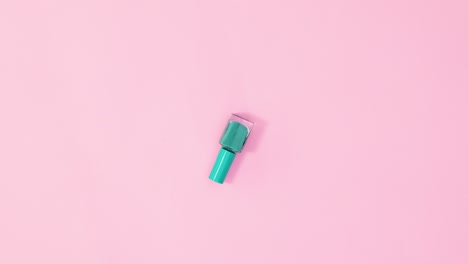 manicure nail polish bottle rotating on pastel pink background. stop motion flat lay