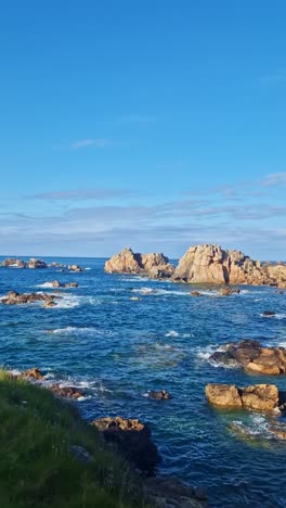 rotating shot of the breton coastline with cliffs, vegetation, rocks, sea, and blue sky