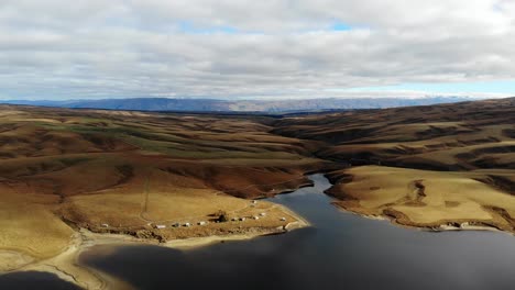 Toma-Elevada-Del-Remoto-Lago-De-Agua-Oscura-Que-Avanza-Lentamente-En-El-Espectacular-Paisaje-Del-Centro-De-Otago-En-Nueva-Zelanda