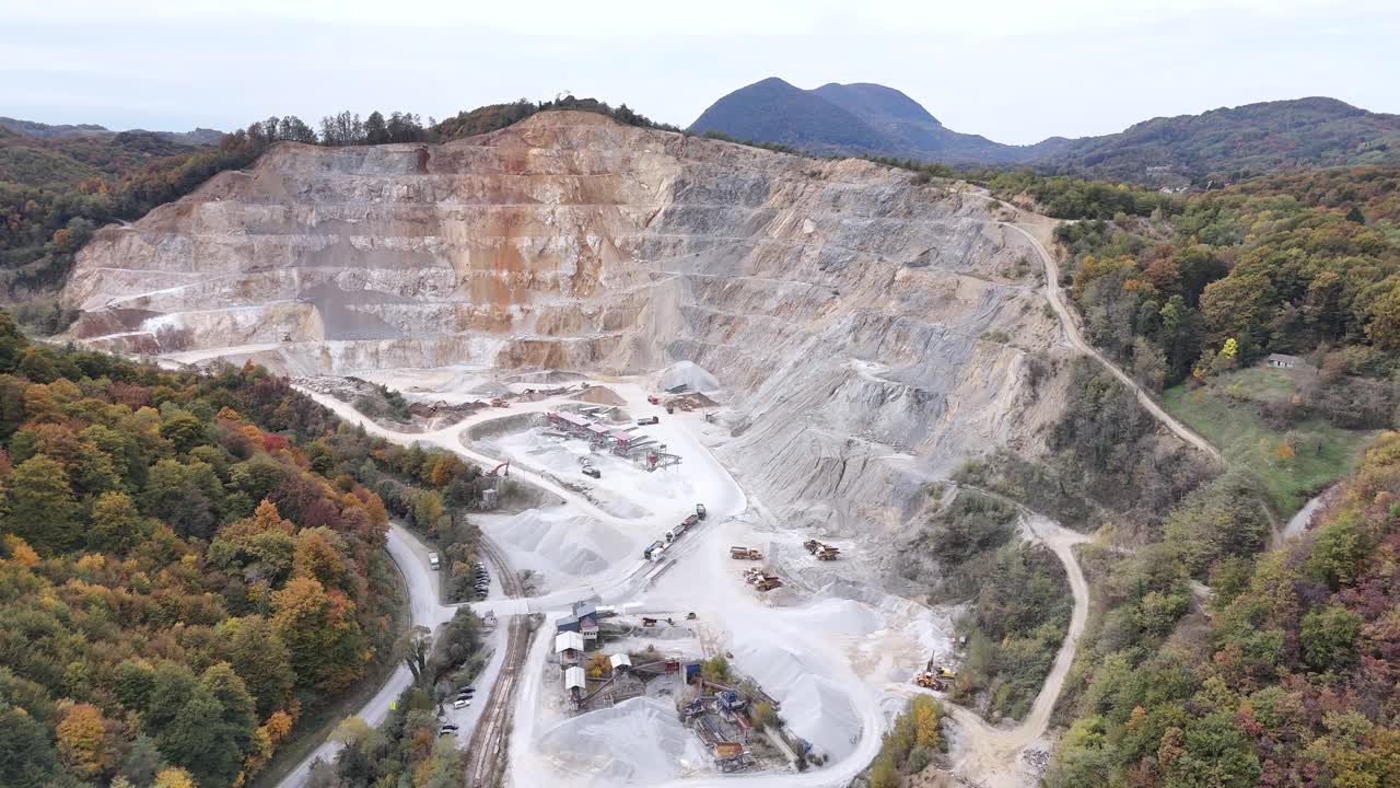 Aerial establishing shot of a quarry site showing industrial landscape with excavation machinery and stone mining area