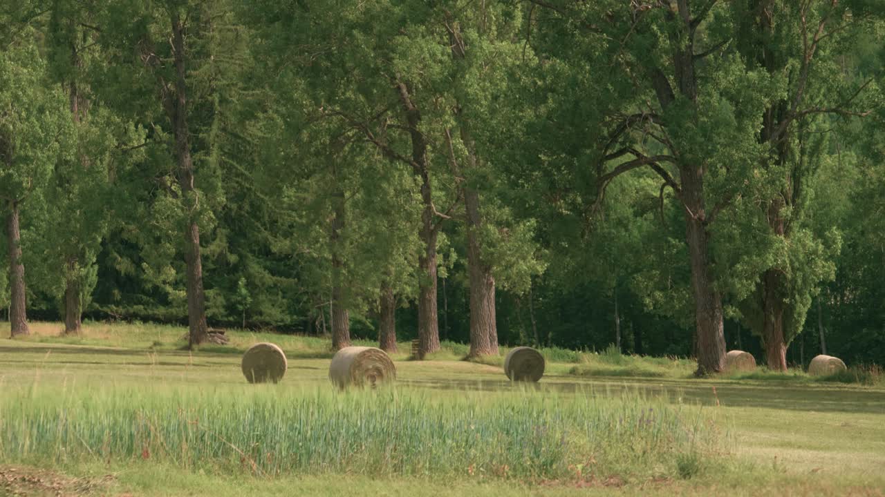 Tilting up from large bales of hay on a farm to the mountain peaks above Barcelonnette, France