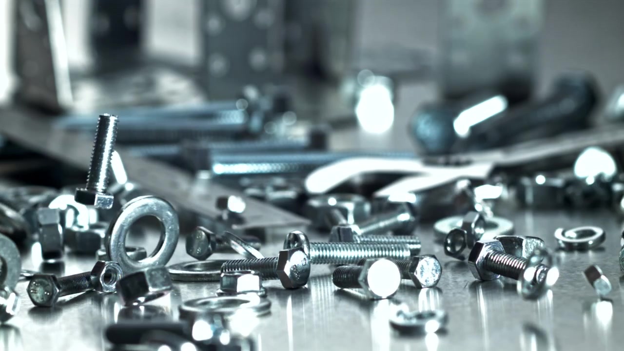 Metal fasteners dropping onto a reflective surface in slow motion