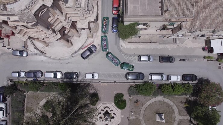 Ripresa aerea dall'alto di un treno turistico che viaggia tra gli edifici a Noto, Sicilia