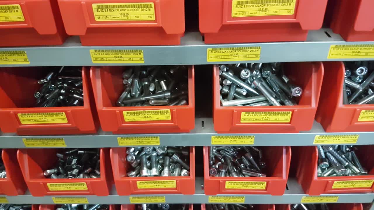 Steel industrial rack with red storage bins with mechanical mounting parts such as nuts, bolts and other parts. CLOSE UP