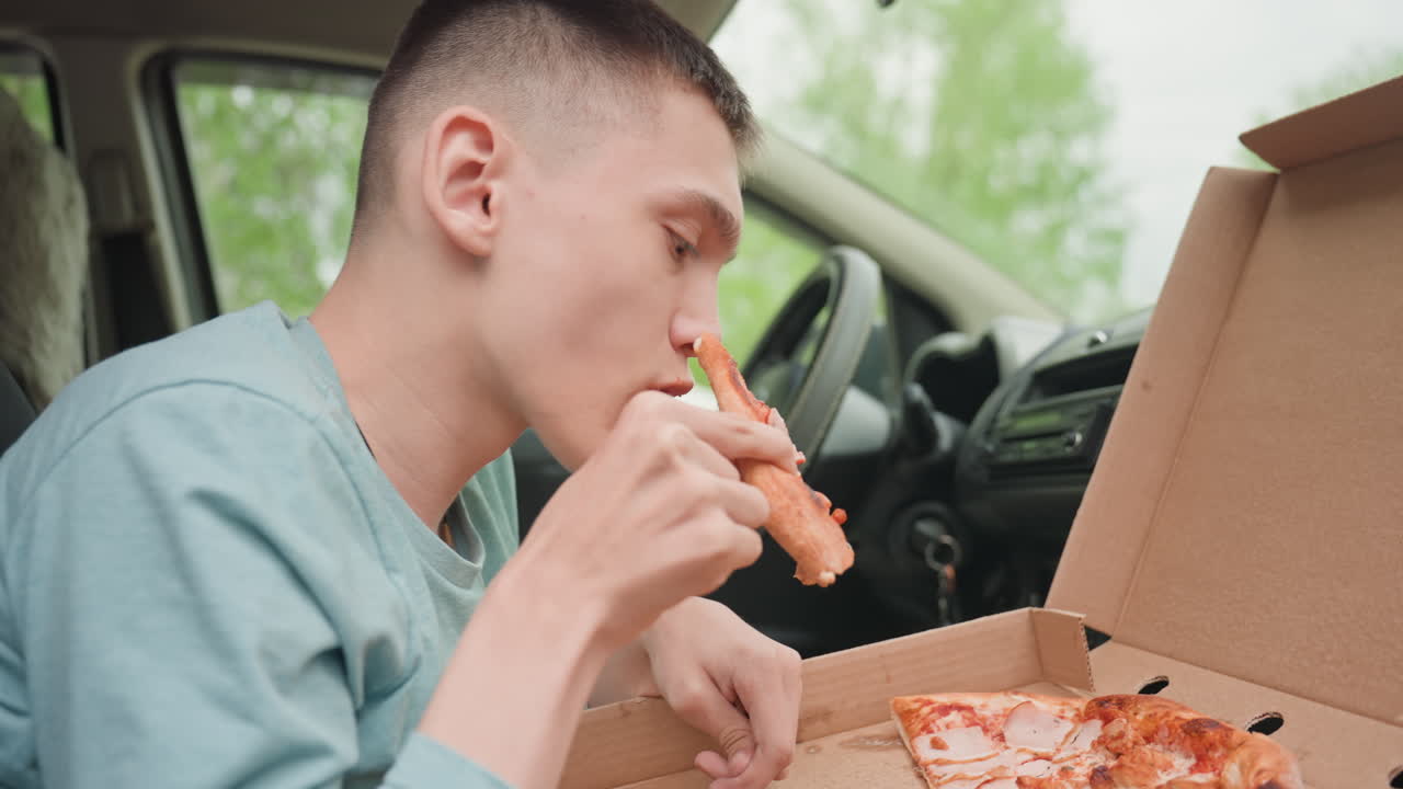 Teen Enjoying Hot Pizza Slice In Parked Car, Leaning Toward Open Box With Green Trees Outside Focused Savoring, Warm Cheese Pull, Casual Roadtrip Vibe, Independent Snack Break After Journey, Relaxed