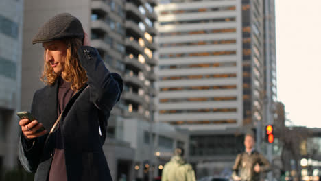 Side-view-of-young-Caucasian-man-using-mobile-phone-in-the-city-street-4k