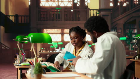 young medical students comparing knowledge and class notes at the library