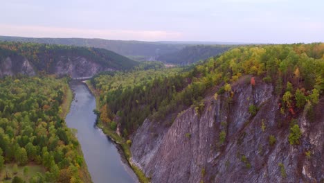 mountains covered with dense forest and a river with blue water flowing through the valley. a haze of mist over the valley. shooting from the air in the evening. natural landscape.