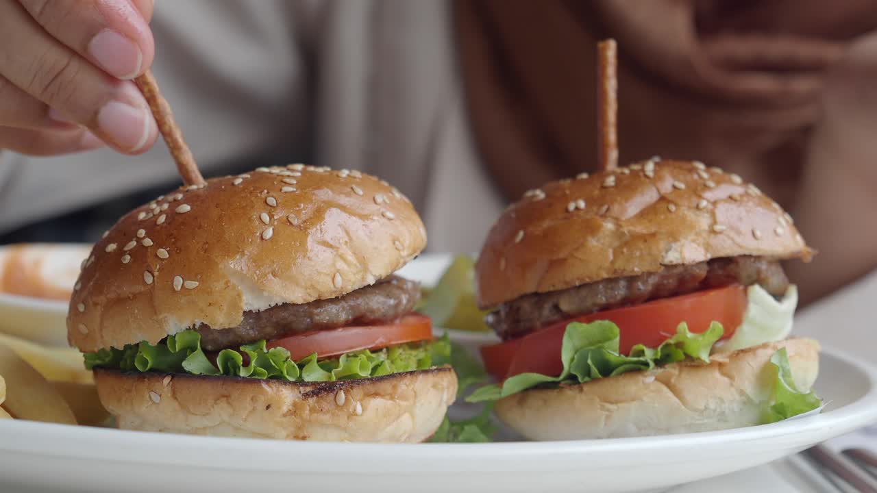 una mujer comiendo deliciosas mini hamburguesas.