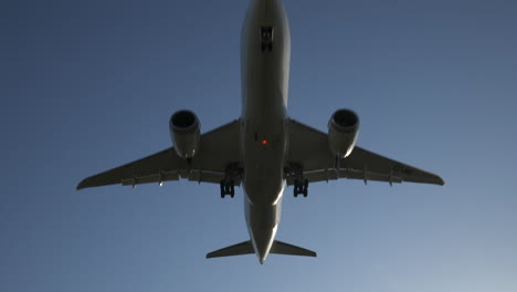 Plane-flying-overhead-closely-followed-to-silhouette,-sun-flare-and-slow-motion