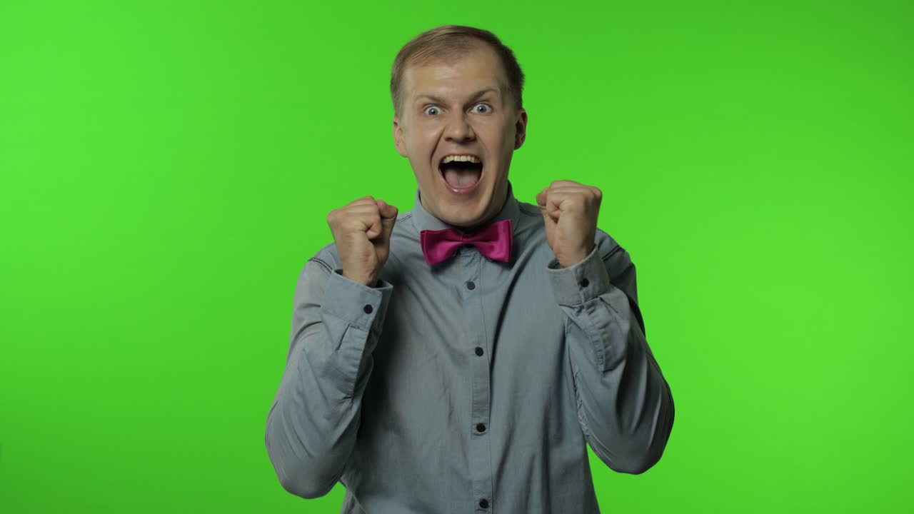 hombre ganando en la lotería, levantando las manos para la victoria, abriendo la boca de asombro, mirando conmocionado