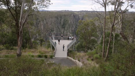 foto tomada a mano de personas en la plataforma de observación en las cataratas de wollomombi, parque nacional oxley wild rivers, nueva gales del sur, australia