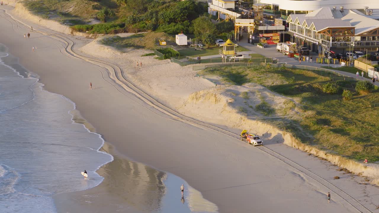 Aerial view of early morning beachgoers and a surf lifesaving club on a sunny Gold Coast beach
