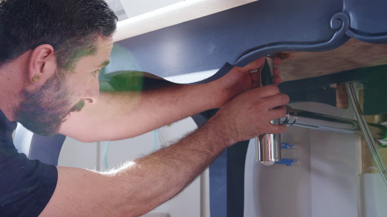 fontanero instalando una nueva trampa de residuos para lavar el lavabo en el baño