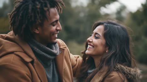 in a peaceful outdoor area, a couple shares laughter and smiles while embracing each other in autumn attire. surrounded by trees, the atmosphere exudes warmth and connection despite the cool weather. their joyful expressions reflect a deep bond as they savor their time together, creating memories th