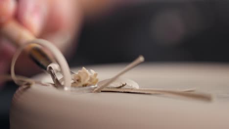 close-up of woman's hands which shaping workpiece with a tool in a pottery studio. clay shavings. slow motion