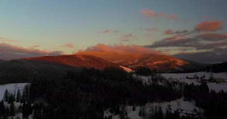 Vista-Aérea-De-Montañas-Y-Bosques-Cubiertos-De-Nieve-Al-Atardecer-En-Invierno-3