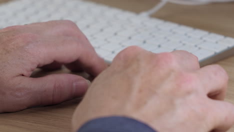 Hands-nervously-tap-beside-keyboard-on-wood-desk,-macro